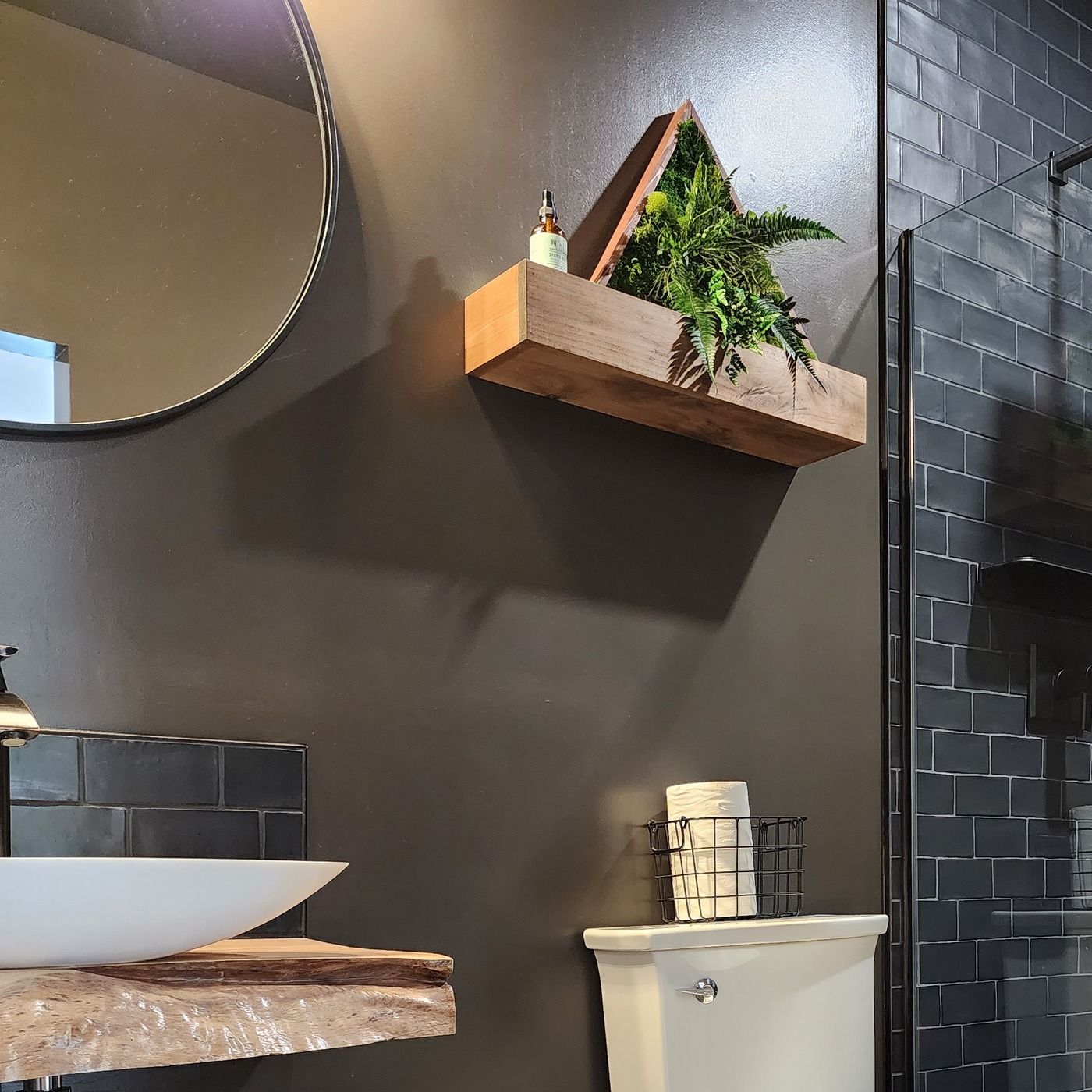 Bathroom in a converted garage suite in Ucluelet, with a live-edge vanity, a wood shelf and a glass shower.